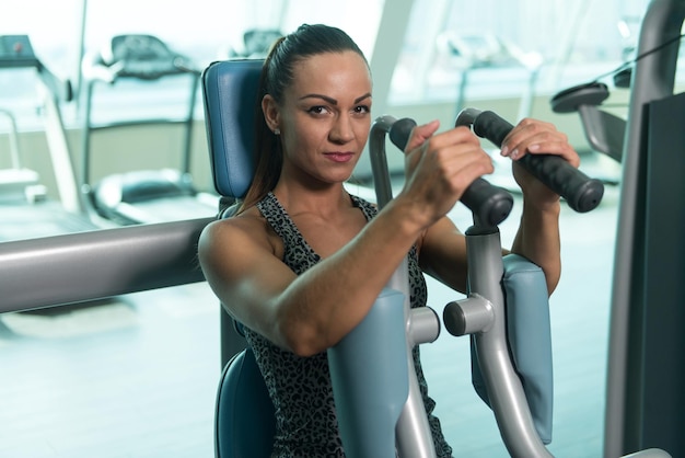 Foto jonge vrouw doet borstoefening in het fitnesscentrum