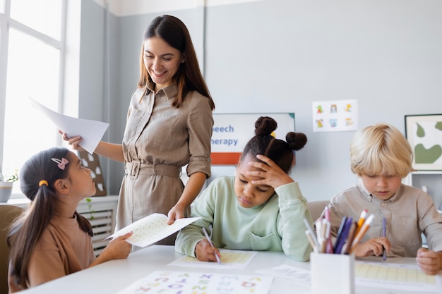 Foto jonge vrouw doet logopedie met kinderen in haar kliniek