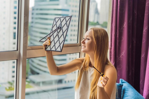 Jonge vrouw doet make-up bij het raam met een panoramisch uitzicht op de wolkenkrabbers en de grote