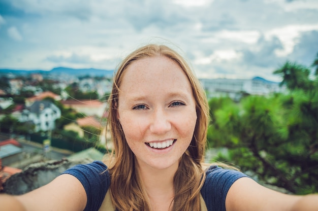 Jonge vrouw doet selfie op de achtergrond van de stad dalat