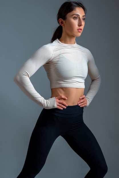 Jonge vrouw doet stretching lunge op grijze muur