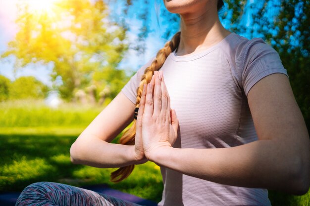 Jonge vrouw doet yoga asana in park meisje stretching oefening in yoga-positie gelukkig en gezonde vrouw zitten in lotuspositie en het beoefenen van yoga meditatie en sport op zonsondergang buitenshuis