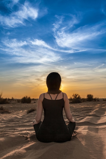 Jonge vrouw doet yoga in de woestijn.