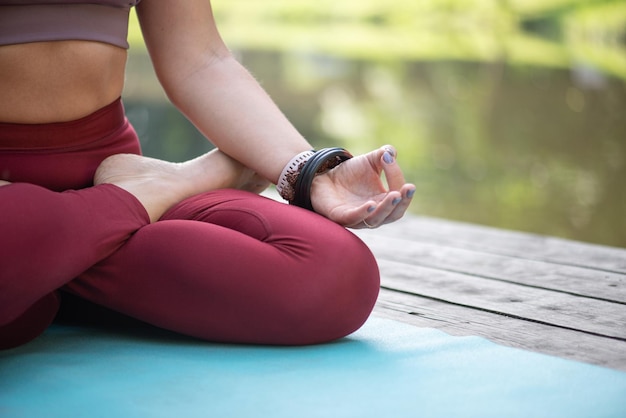 Jonge vrouw doet yoga in het park op het gras.