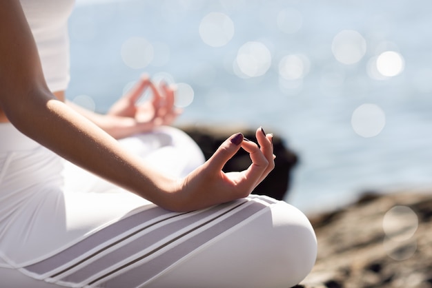 Jonge vrouw doet yoga in het strand met witte kleding