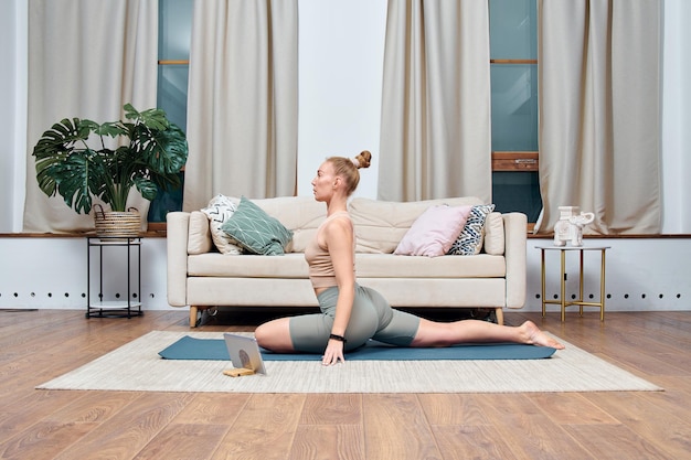 Foto jonge vrouw doet yoga-oefening in een kamer thuis