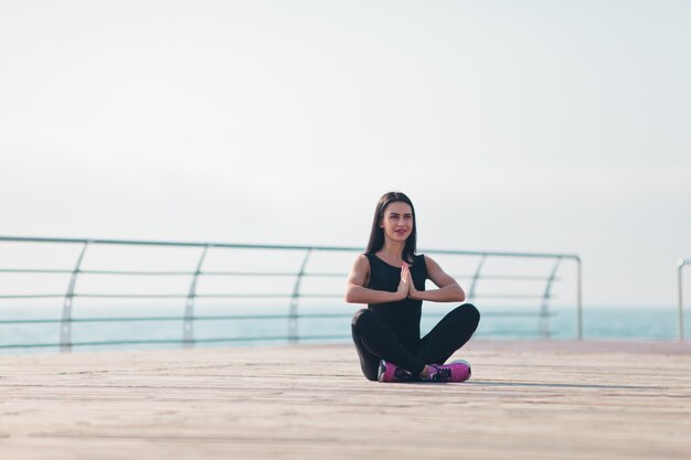 Jonge vrouw doet yoga op het strand