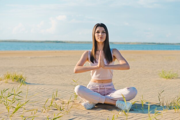 Jonge vrouw doet yoga op het strand