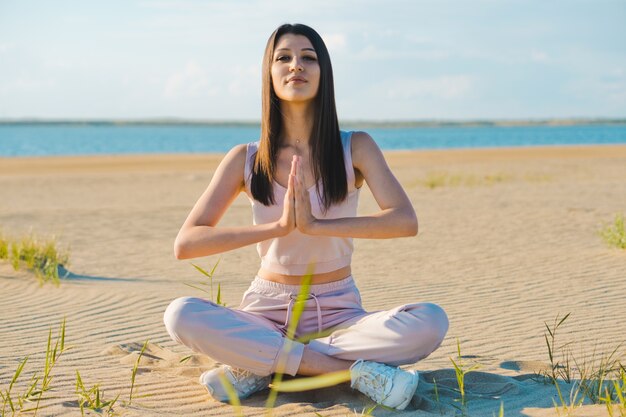 Jonge vrouw doet yoga op het strand