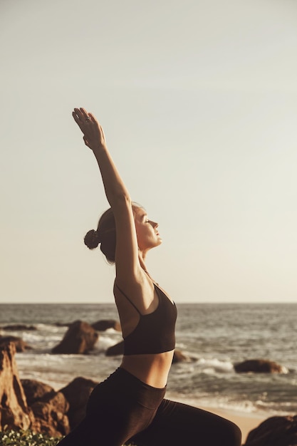 Jonge vrouw doet yoga voor een gezonde levensstijl op zeestrand