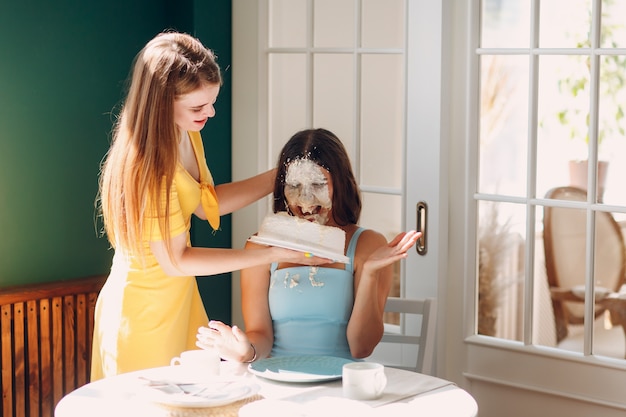 Jonge vrouw dompelt gezicht in witte cake met room. Gelukkig verjaardagsconcept.