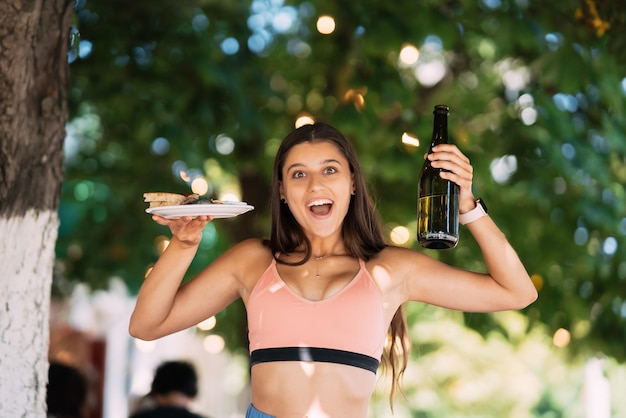 Jonge vrouw draagt een bord snacks en een drankje in handen