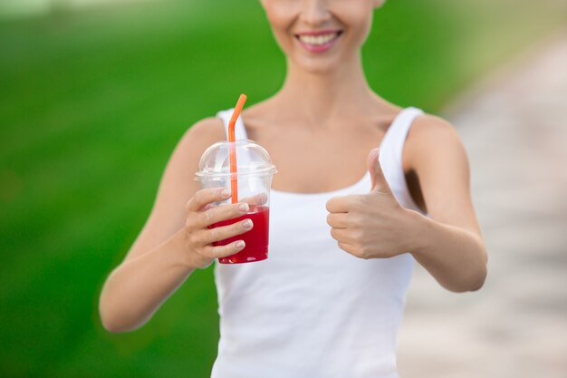 Jonge vrouw drink smoothie gezonde detox buitenshuis