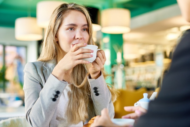 Jonge vrouw drinken koffie tijdens bijeenkomst in Cafe