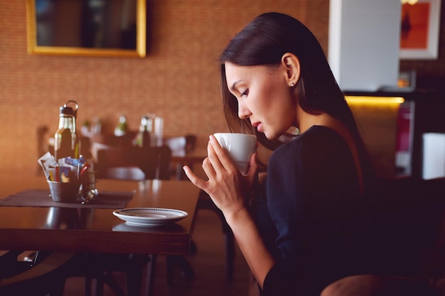 Jonge vrouw drinkt in een restaurant.