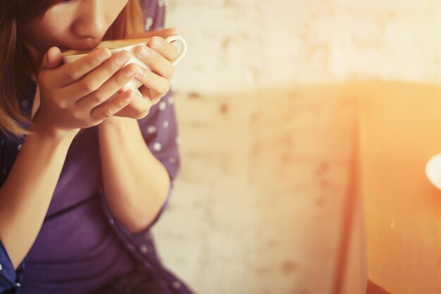 Foto jonge vrouw drinkt koffie bij de muur.