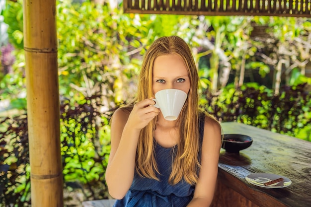 Jonge vrouw drinkt koffie Luwak in het prieel.