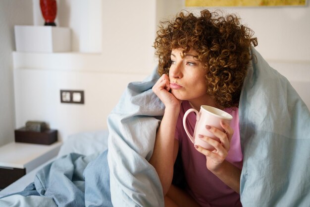 Foto jonge vrouw drinkt koffie thuis.