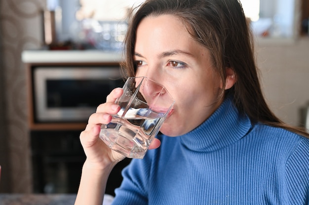 Jonge vrouw drinkt water uit een glas