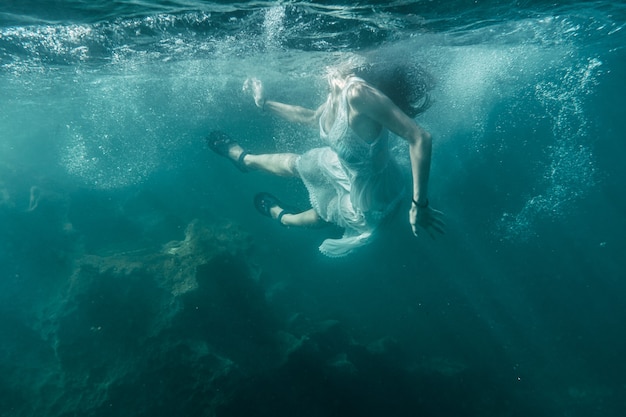 Jonge vrouw duiken met een witte jurk