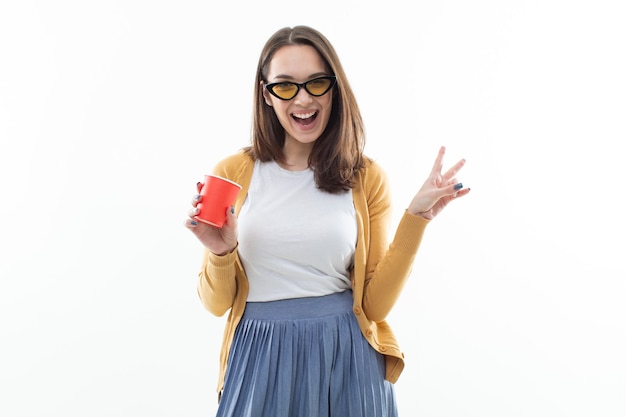 Jonge vrouw een gele trui drinkt koffie uit een rode kop