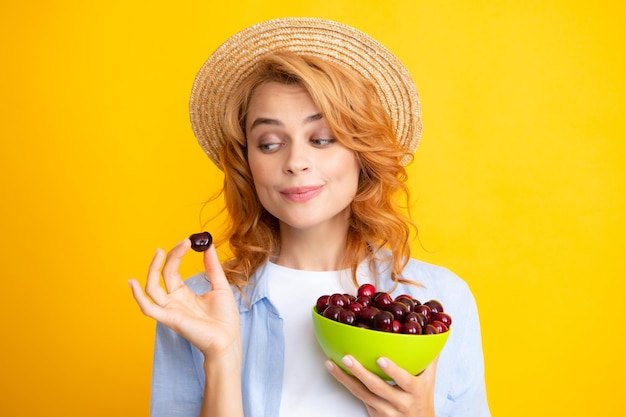 Jonge vrouw eet zoete kersen Portret van een mooi meisje met kers op gele achtergrond Zomerfruit plukseizoen Natuurlijke vitamines