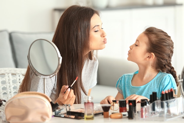 Jonge vrouw en haar dochtertje die thuis make-up aanbrengen