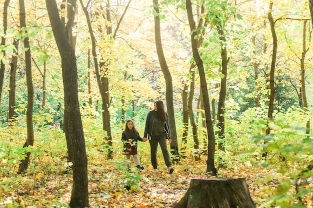 Jonge vrouw en haar kindmeisje die door park alleenstaande ouder en moederschapsconcept lopen