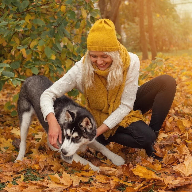 Jonge vrouw en hond husky plezier buiten in het herfstpark