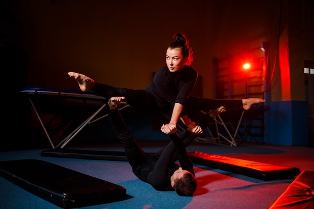 Jonge vrouw en man gymnasten doen acrobatische oefeningen in de sportschool. sportactiviteiten, gezonde levensstijl