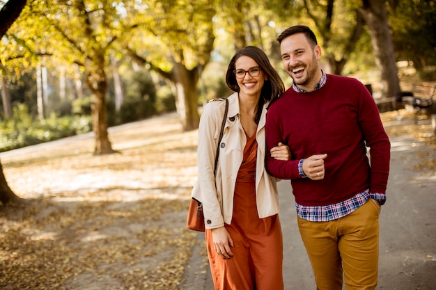 Jonge vrouw en man lopen in stadspark hand in hand