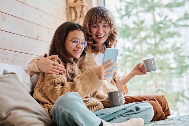 Jonge vrouw en tienermeisje surfen op het internet op een smartphone