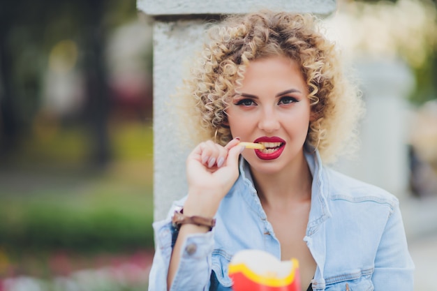 Jonge vrouw eten franse frietjes straatvoedsel