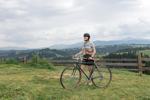 Jonge vrouw fietser geniet van het prachtige uitzicht op de groene bergen trail