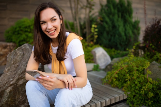 Jonge vrouw freelancer communiceert met klanten aan de telefoon zittend in een groen park.