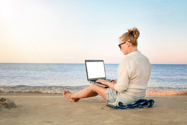 Jonge vrouw freelancer werkt aan de kust. vrouw met laptopcomputer op het strand.