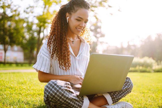 Jonge vrouw freelancer zittend op groen gras met laptop Onderwijs online