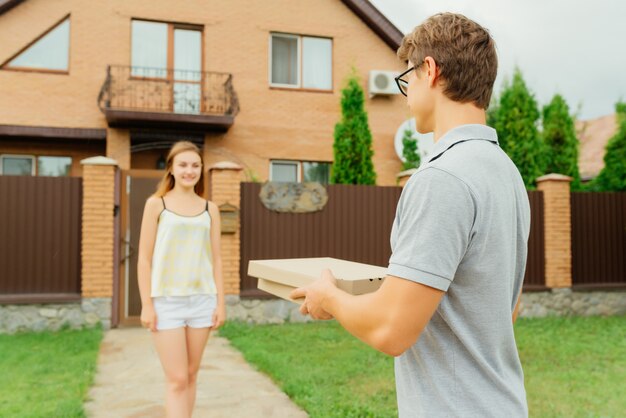 Jonge vrouw gaat een pizza halen bij een koerier bij de privéwoning