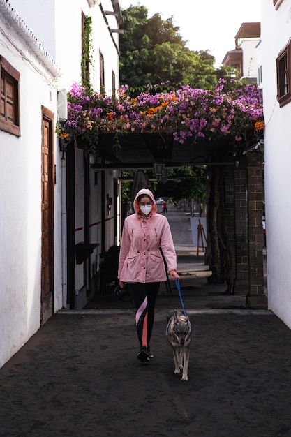 Jonge vrouw gaat wandelen met hond door de straat terwijl het regent