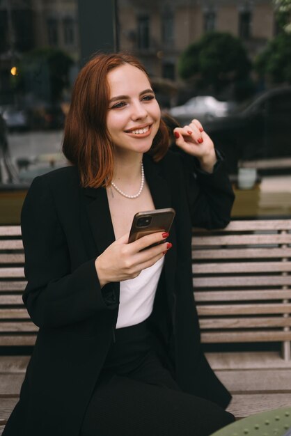 Jonge vrouw gebruikt de telefoon in het straatcafé