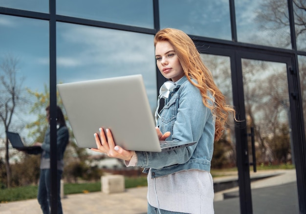 Jonge vrouw gebruikt onderweg een laptop in de buurt van het zakencentrum