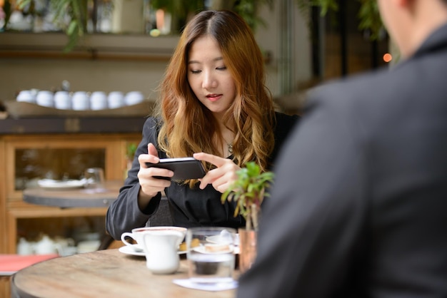 Jonge vrouw gebruikt telefoon in restaurant
