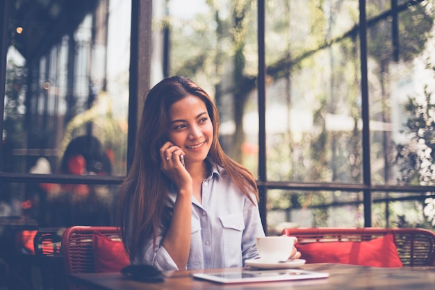 Jonge vrouw gebruikt telefoon terwijl ze in een café zit