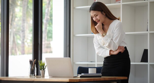 Foto jonge vrouw gebruikt telefoon terwijl ze op tafel staat