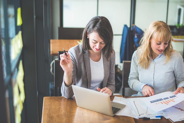 Foto jonge vrouw gebruikt telefoon terwijl ze op tafel zit