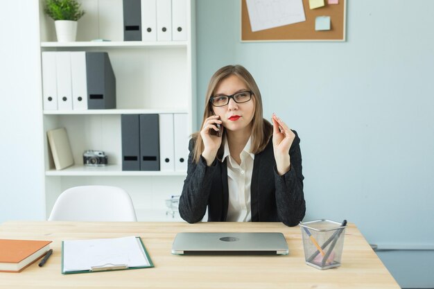 Foto jonge vrouw gebruikt telefoon terwijl ze op tafel zit