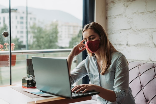 Jonge vrouw gebruikt telefoon terwijl ze op tafel zit