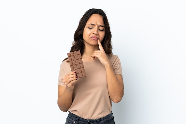 Jonge vrouw geïsoleerd een chocoladetablet nemen en twijfels hebben