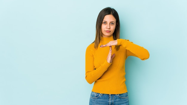 Jonge vrouw geïsoleerd op blauw met een time-outgebaar.