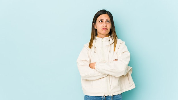 Jonge vrouw geïsoleerd op blauwe achtergrond moe van een zich herhalende taak.